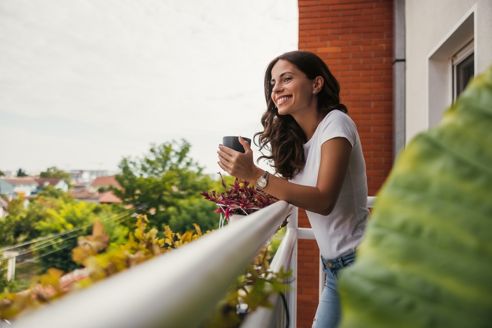 A woman drinks her morning coffee on a balcony.