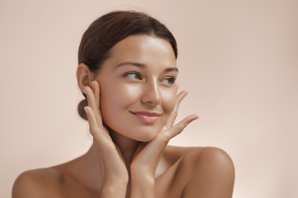 A young woman frames her face with her hands