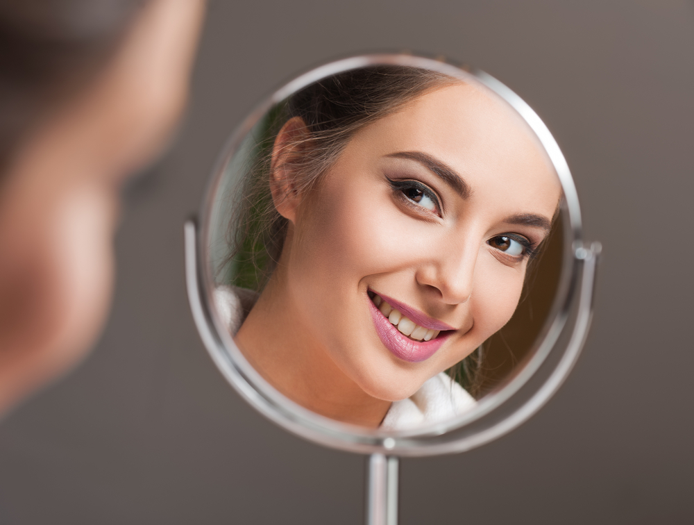 beautiful woman looking at herself in the mirror smiling