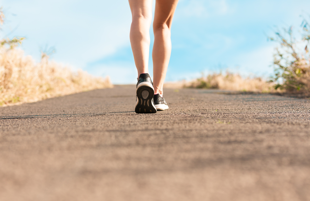 A woman's legs walking along a path in tennis shoes