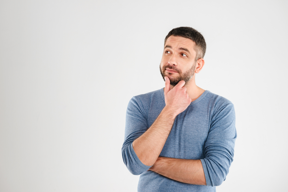 A man in blue shirt crossing his arms and holding his chin thoughtfully.