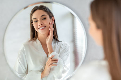 A woman with perfect skin looks in the mirror after microneedling treatments