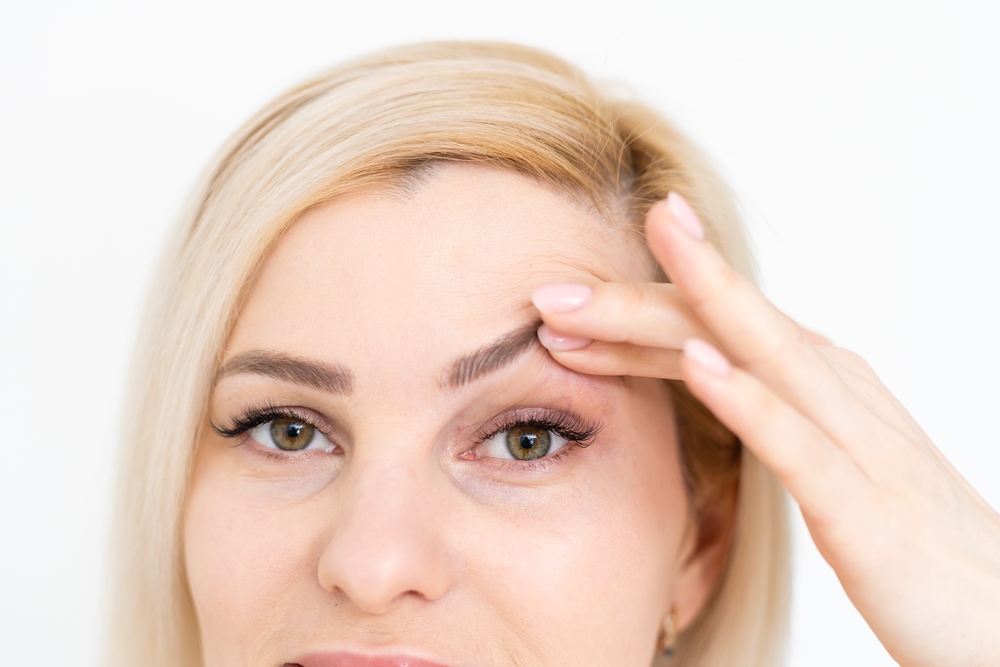 woman lifting up drooping eyelid with her hand