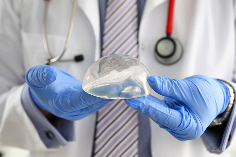 Doctor holding a silicone breast implant.