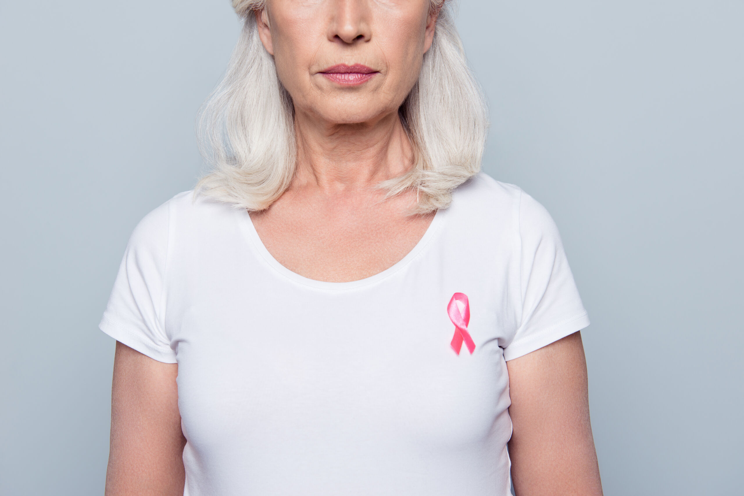 Woman wearing a white shirt with a breast cancer awarness pink ribbon.