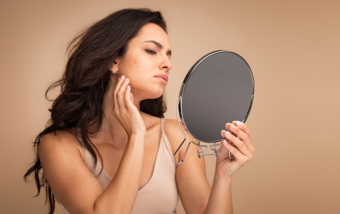 A woman examining her skin in a mirror.